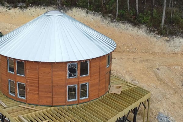 From above: the metal roof cone on the building, with the wraparound deck framed on steel piers